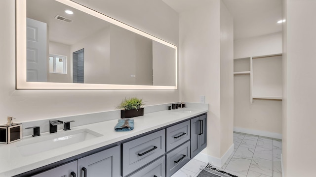 bathroom with baseboards, marble finish floor, a sink, visible vents, and double vanity