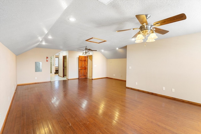 unfurnished living room with a textured ceiling, wood-type flooring, lofted ceiling, ceiling fan, and electric panel