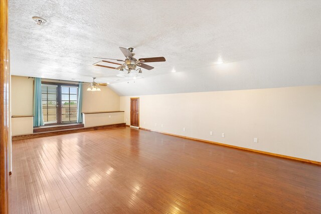 empty room with lofted ceiling, ceiling fan, hardwood / wood-style floors, and a textured ceiling