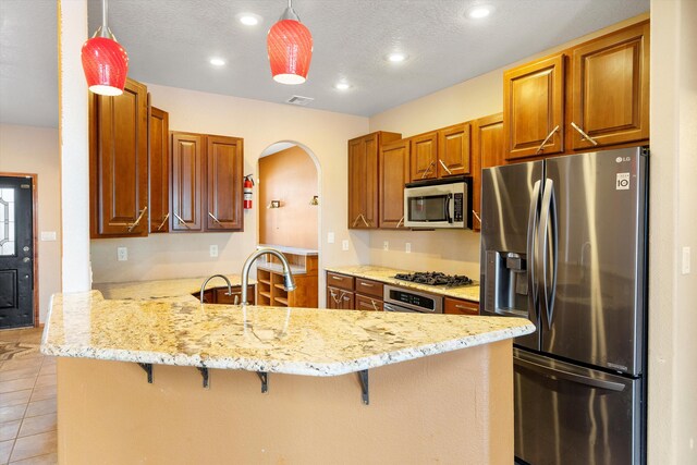 kitchen with stainless steel appliances, hanging light fixtures, and kitchen peninsula