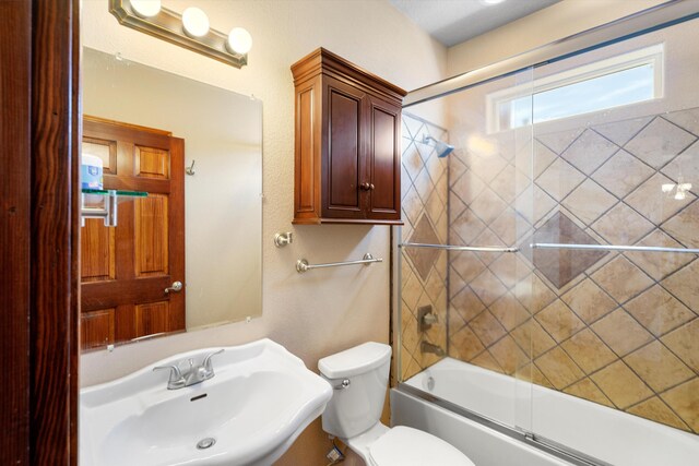 full bathroom featuring toilet, combined bath / shower with glass door, and sink