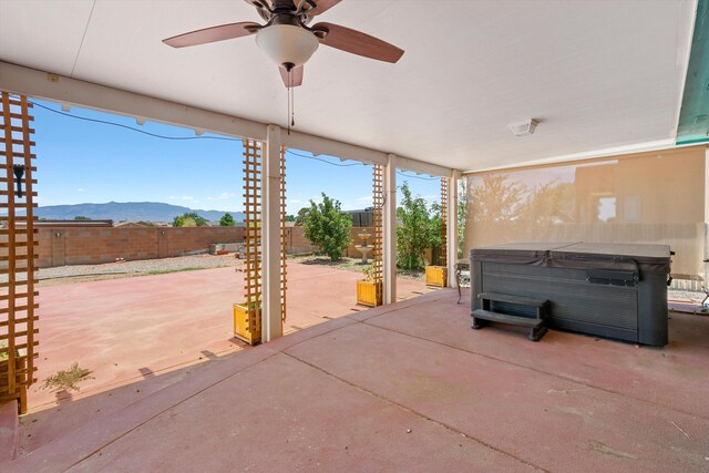 view of patio with ceiling fan, a mountain view, and a hot tub