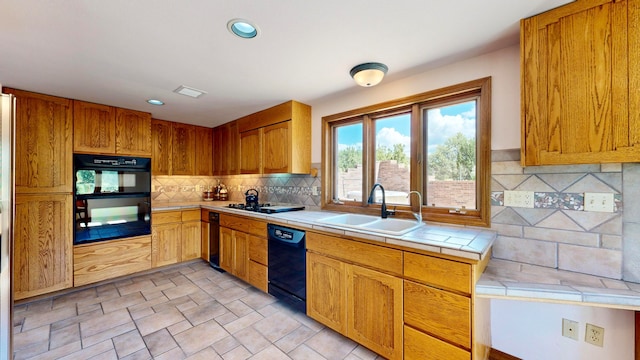 kitchen featuring black appliances, backsplash, tile counters, and sink