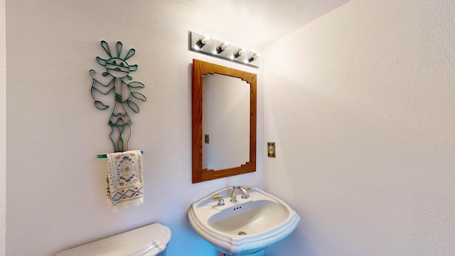 bathroom with toilet, a textured ceiling, and sink