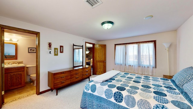 carpeted bedroom with ensuite bathroom and sink