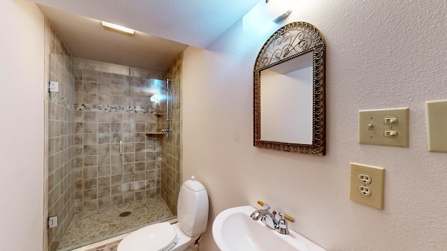 bathroom featuring tiled shower, toilet, and sink