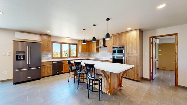 kitchen featuring stainless steel appliances, a kitchen island, sink, a breakfast bar area, and wall chimney range hood