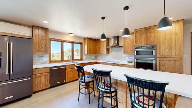 kitchen featuring appliances with stainless steel finishes, a breakfast bar area, wall chimney exhaust hood, and tasteful backsplash