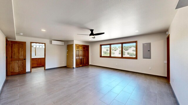 unfurnished room featuring a wall unit AC, ceiling fan, and electric panel