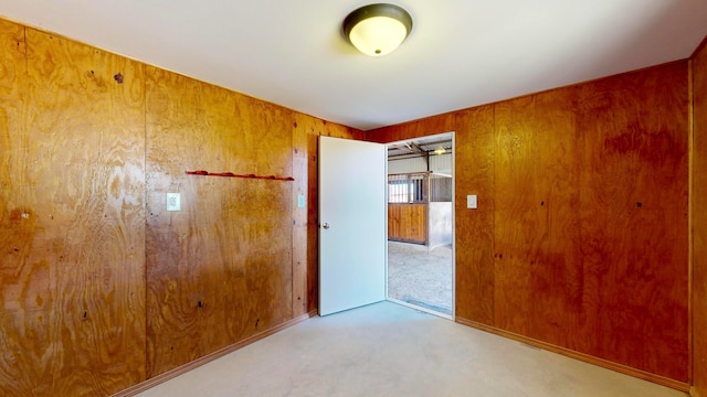 spare room with carpet and wooden walls