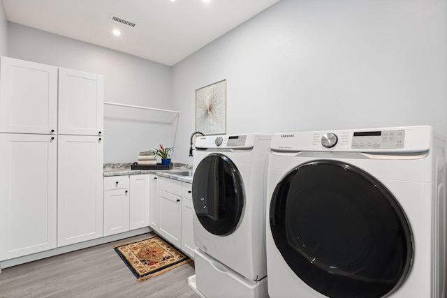 washroom featuring light hardwood / wood-style flooring, cabinets, and separate washer and dryer