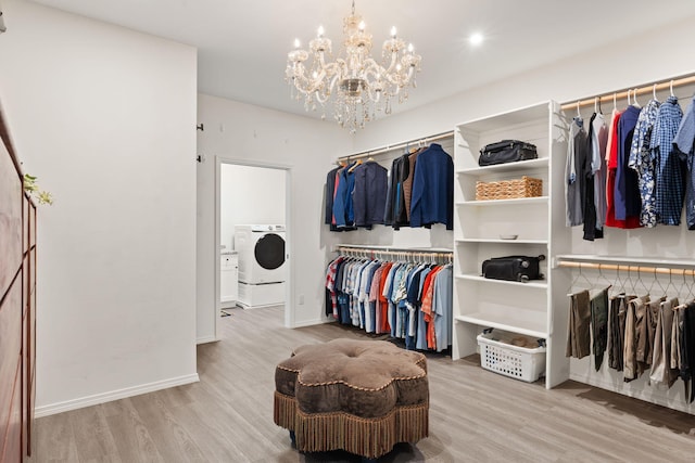 walk in closet with light hardwood / wood-style flooring, washer / dryer, and a chandelier