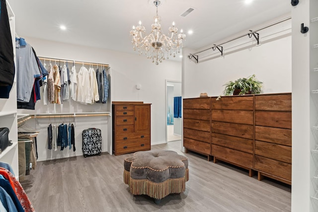 spacious closet featuring light hardwood / wood-style flooring and a notable chandelier