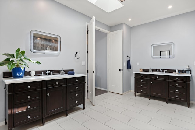 bathroom featuring tile patterned flooring, vanity, and a skylight