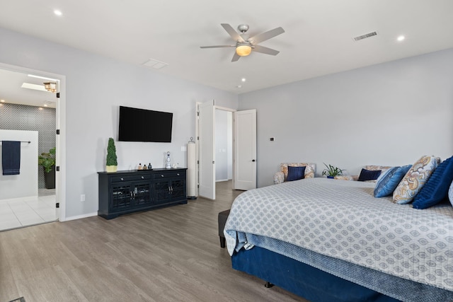 bedroom with ceiling fan, light hardwood / wood-style floors, and ensuite bath