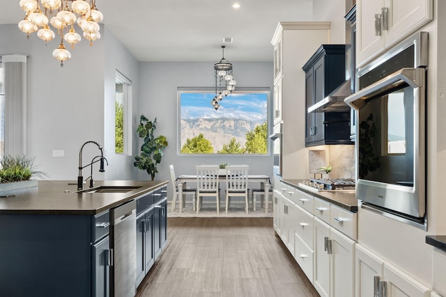 kitchen with white cabinetry, a chandelier, decorative light fixtures, sink, and appliances with stainless steel finishes