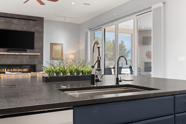 kitchen with ceiling fan, sink, and a tile fireplace