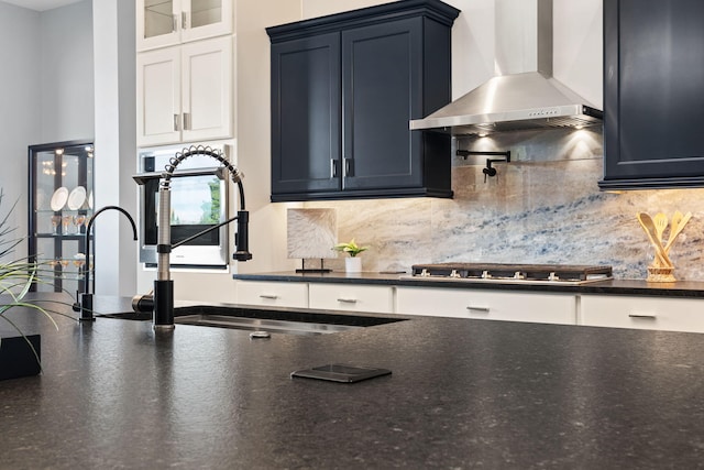 kitchen featuring stainless steel gas stovetop, wall chimney exhaust hood, tasteful backsplash, and sink