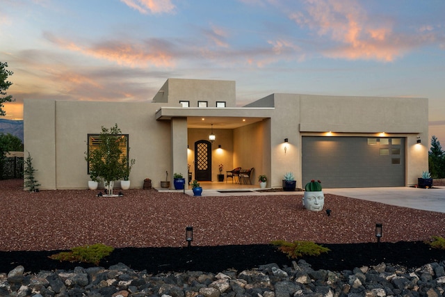 pueblo revival-style home with stucco siding, driveway, and a garage