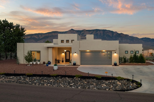 pueblo-style home with central AC, stucco siding, concrete driveway, a garage, and a mountain view