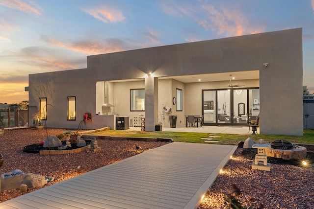 back house at dusk with a patio area and an outdoor fire pit