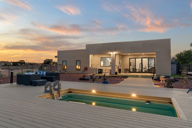 pool at dusk with an outdoor hangout area and a deck