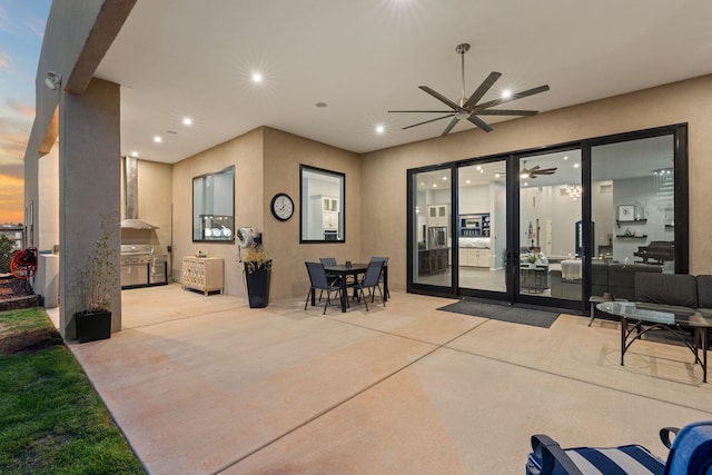 patio terrace at dusk featuring area for grilling and ceiling fan