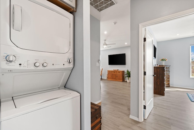 clothes washing area featuring light hardwood / wood-style flooring, ceiling fan, and stacked washer and dryer