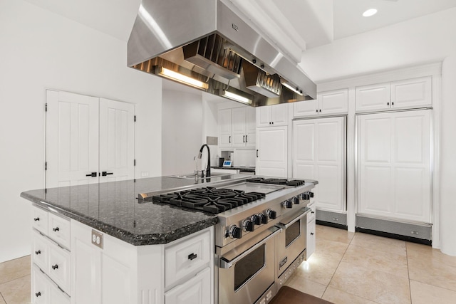 kitchen with range with two ovens, light tile patterned floors, island exhaust hood, a center island, and white cabinetry