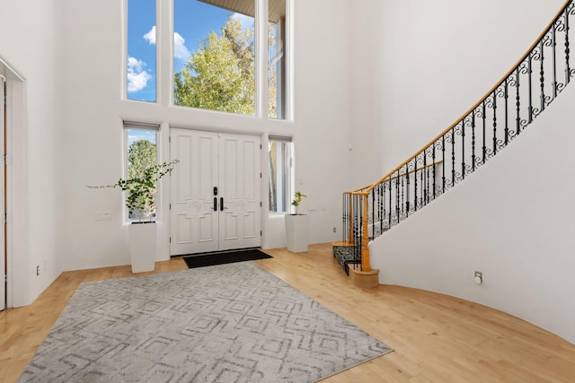 foyer with a towering ceiling, stairs, and wood finished floors