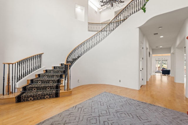 stairway featuring a towering ceiling, wood finished floors, and recessed lighting