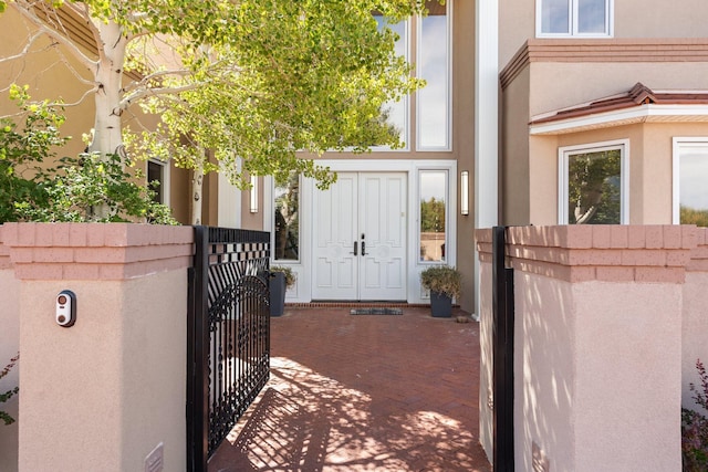 view of exterior entry featuring a gate, fence, and stucco siding