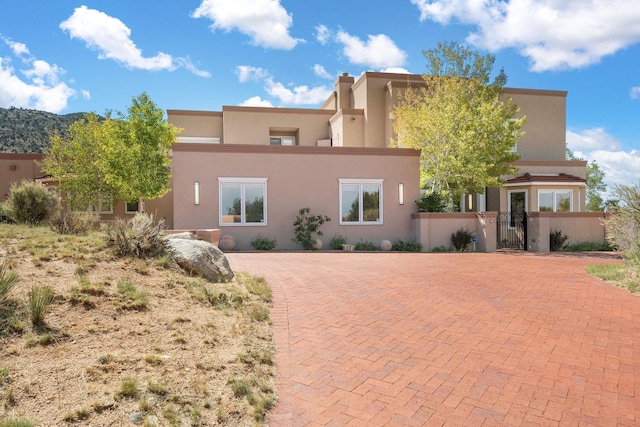 pueblo-style home with a fenced front yard, a gate, and stucco siding