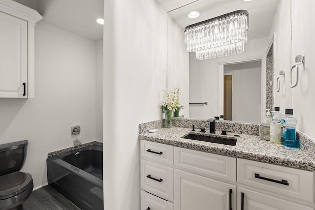 full bath featuring toilet, a notable chandelier, wood finished floors, vanity, and a bath