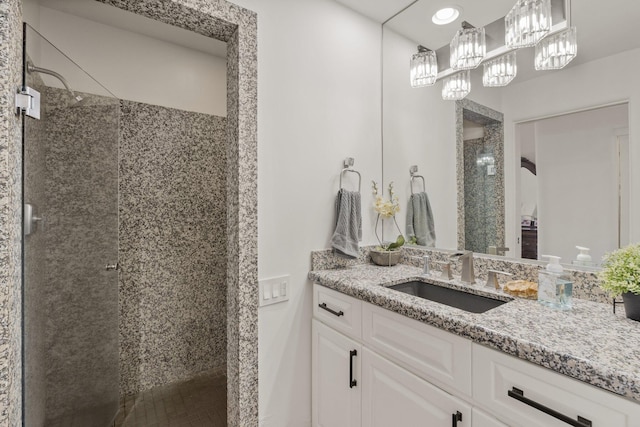 full bathroom featuring tiled shower and vanity