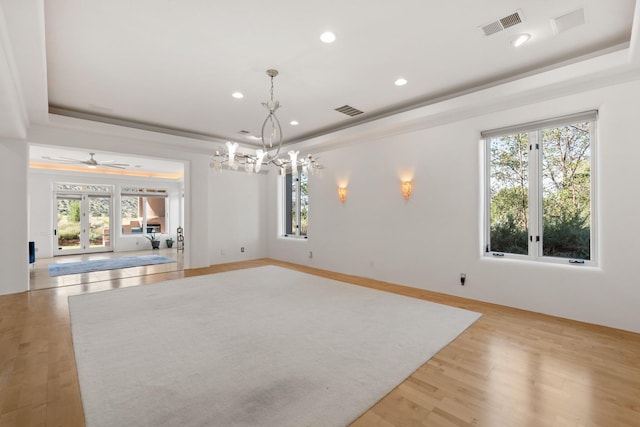 spare room featuring a raised ceiling, visible vents, and light wood-style flooring