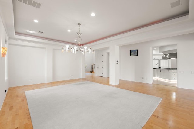 interior space featuring a tray ceiling, visible vents, and light wood-style floors