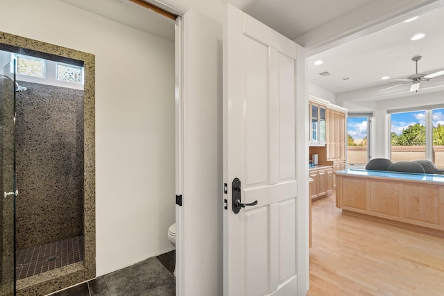 bathroom with a stall shower, a ceiling fan, toilet, wood finished floors, and recessed lighting