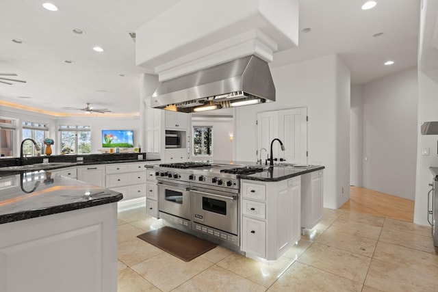 kitchen with light tile patterned floors, wall chimney exhaust hood, a sink, and stainless steel appliances