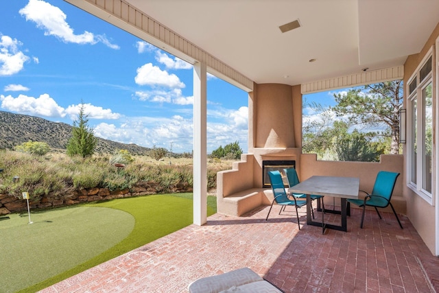 view of patio featuring outdoor dining area, visible vents, a mountain view, and exterior fireplace