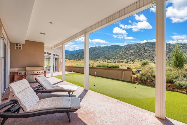 view of patio with visible vents, exterior kitchen, area for grilling, and a mountain view