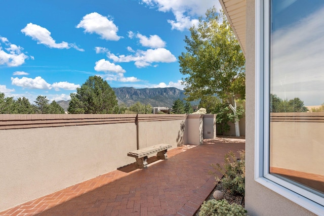 view of patio with fence and a mountain view