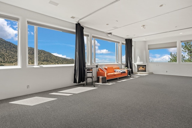 interior space featuring plenty of natural light, a glass covered fireplace, and a mountain view