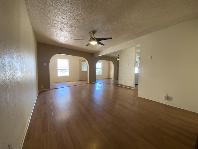 unfurnished living room with ceiling fan, a textured ceiling, and dark hardwood / wood-style flooring