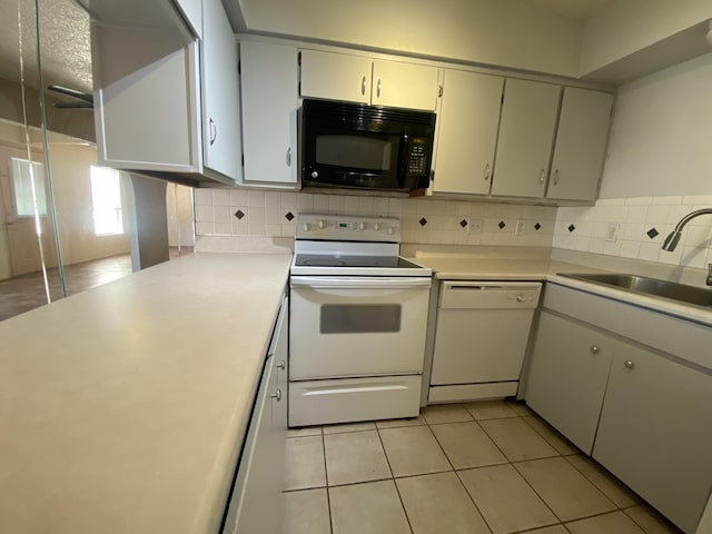 kitchen with white appliances, light tile patterned floors, sink, and decorative backsplash