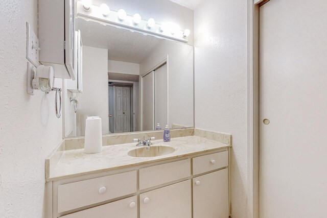 bathroom featuring vanity, a textured ceiling, a shower with shower door, and toilet