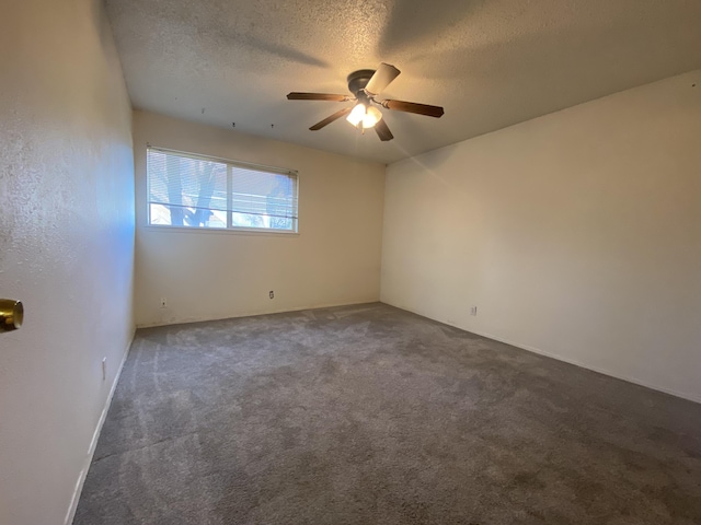 empty room featuring ceiling fan, a textured ceiling, and dark colored carpet