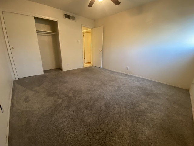 unfurnished bedroom featuring dark carpet, a closet, and ceiling fan