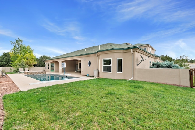 rear view of house with a yard, a fenced in pool, and a patio