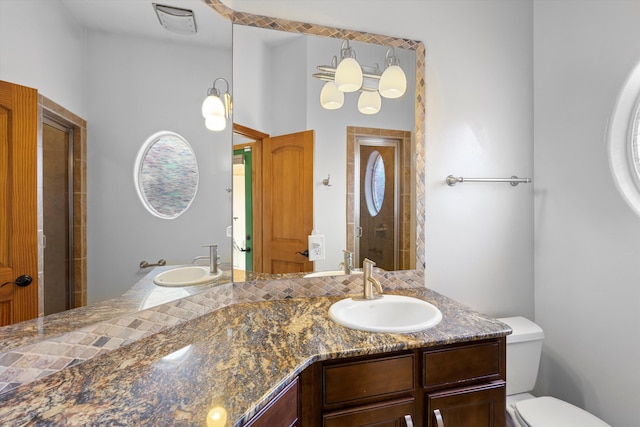 bathroom featuring a shower with shower door, toilet, and vanity